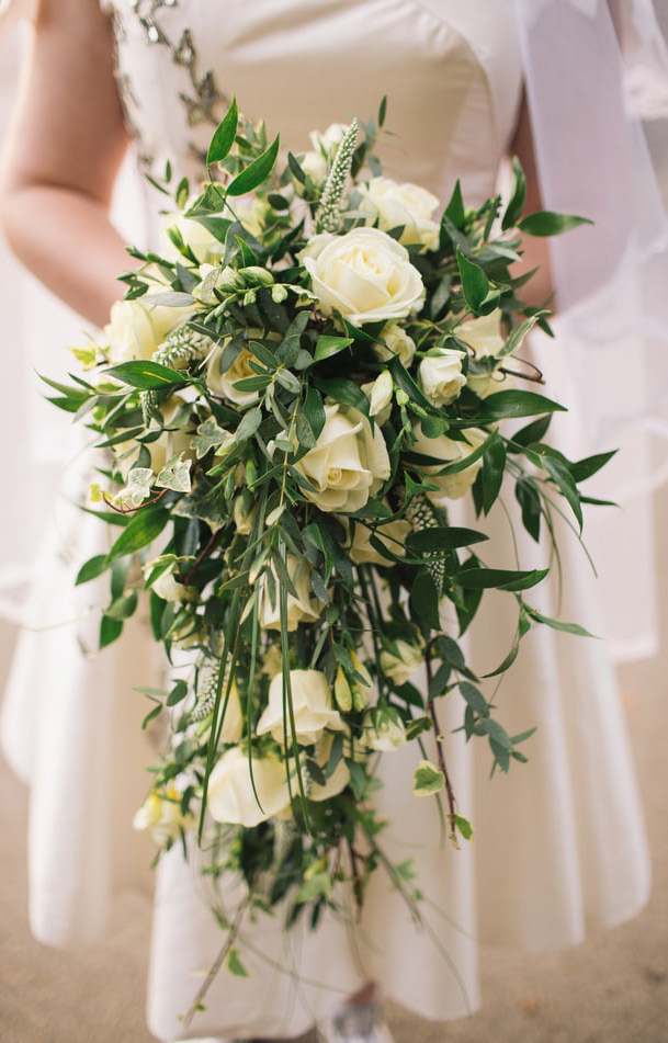 Bride holding a bouquet of white roses.