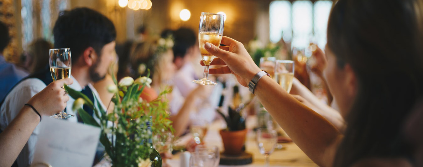 Wedding guests raise their champagne glasses in a toast during a reception.