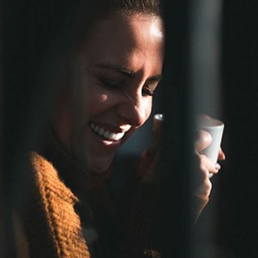 girl laughing while holding a mug
