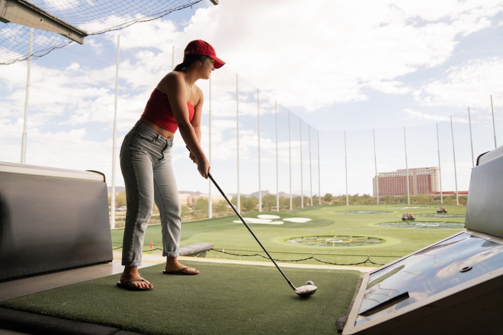 Woman teeing off at a TopGolf facility.