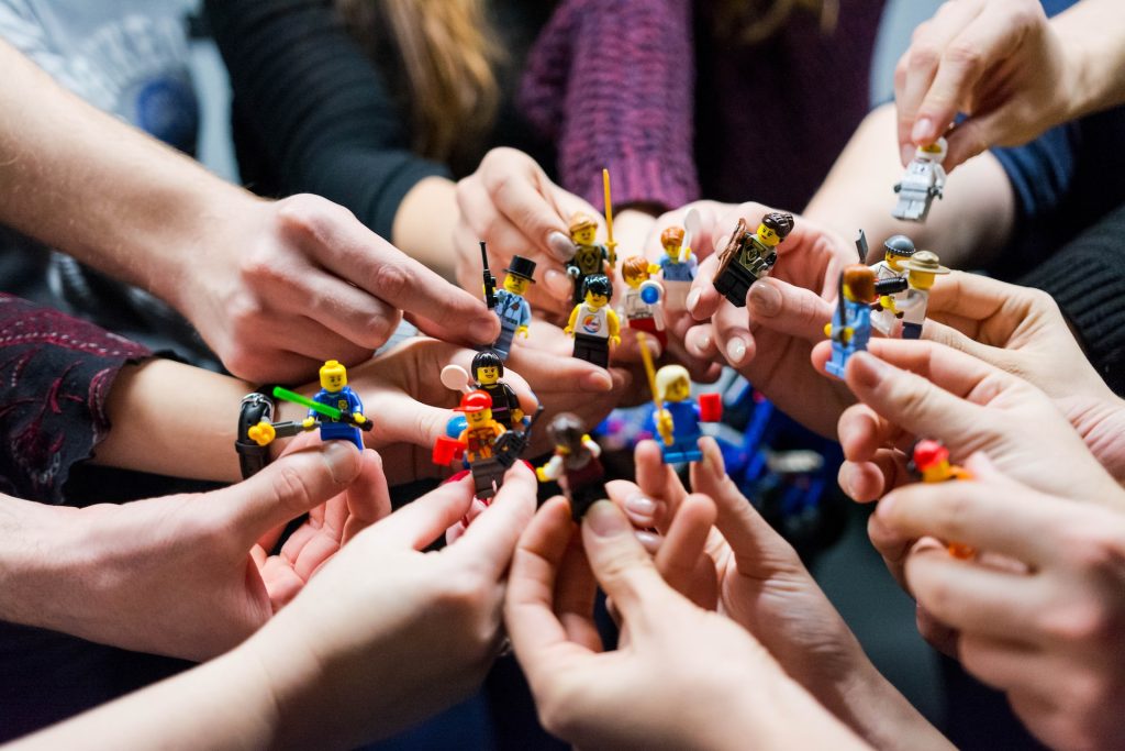 Close of up many hands holding up Lego figures.