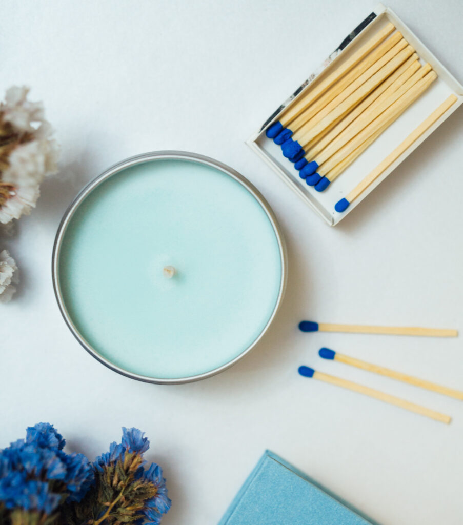 Baby blue candle with matches and flowers on a table.