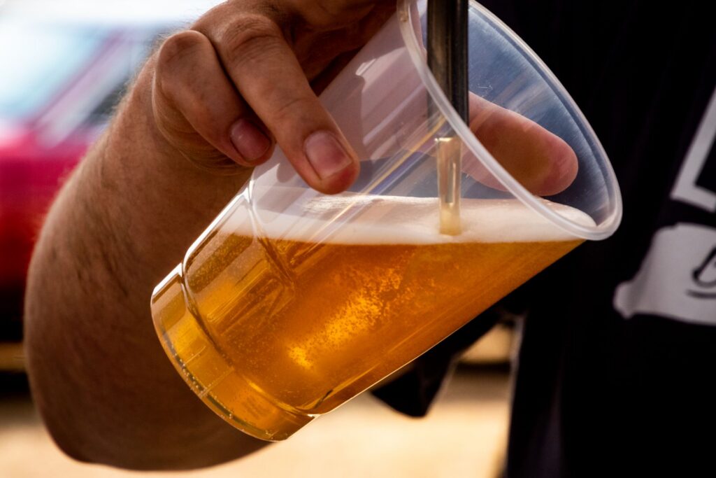 A beer being poured into a plastic cup.