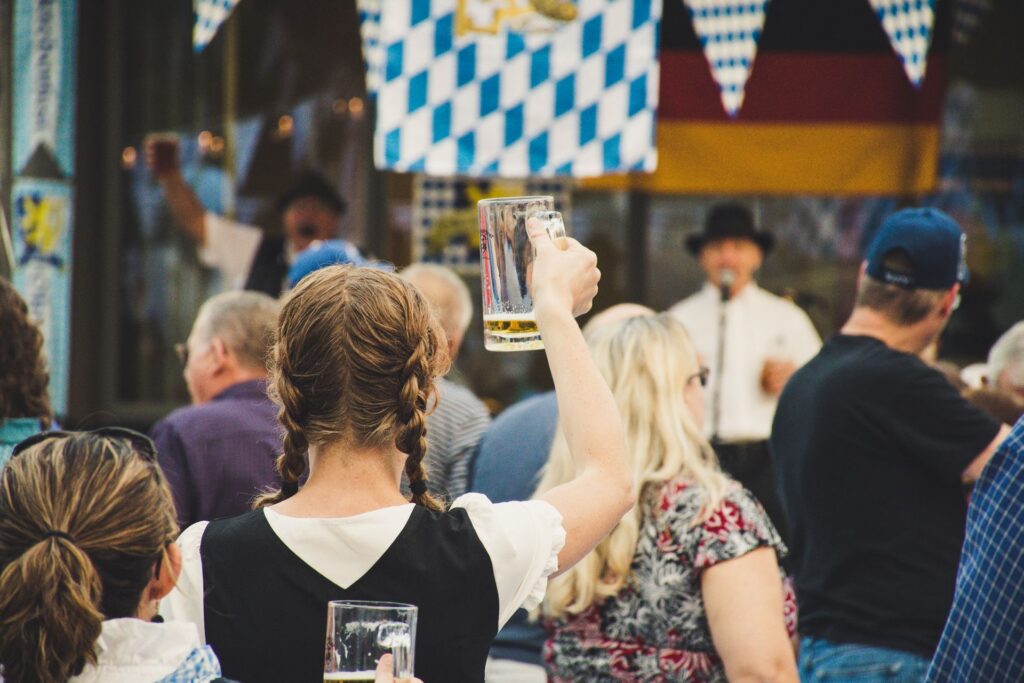 Woman raising a glass of beer in a crowd at Oktoberfest.